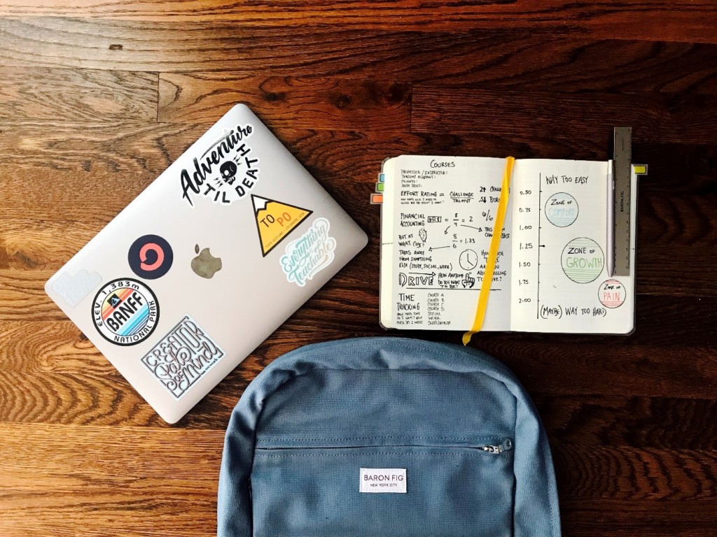 Closed Laptop Next to Open Notebook Filled with Colourful Notes 
